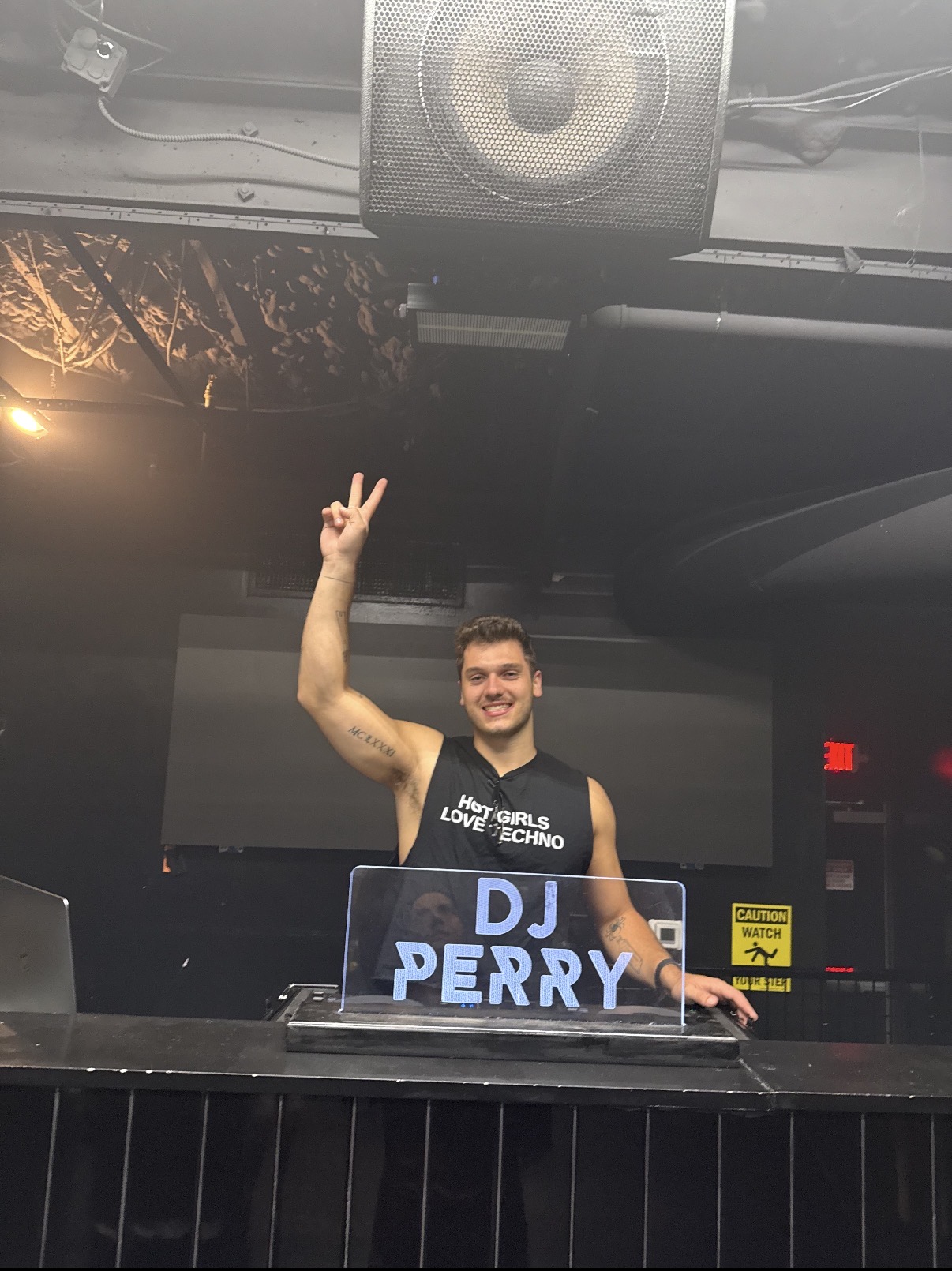 Perry behind the decks with peace sign